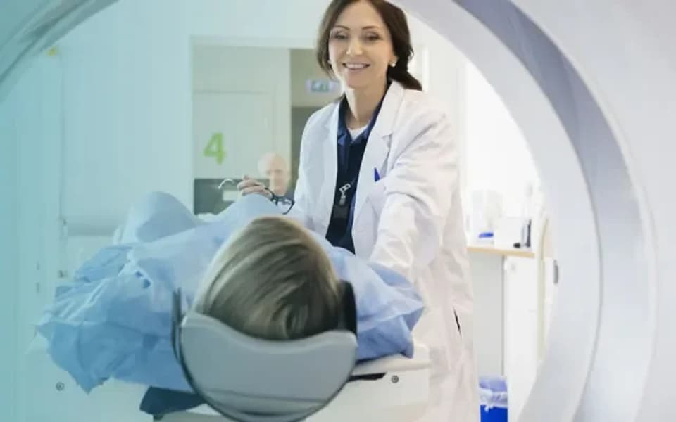 Médica acompanha paciente posicionada no aparelho de ressonância magnética